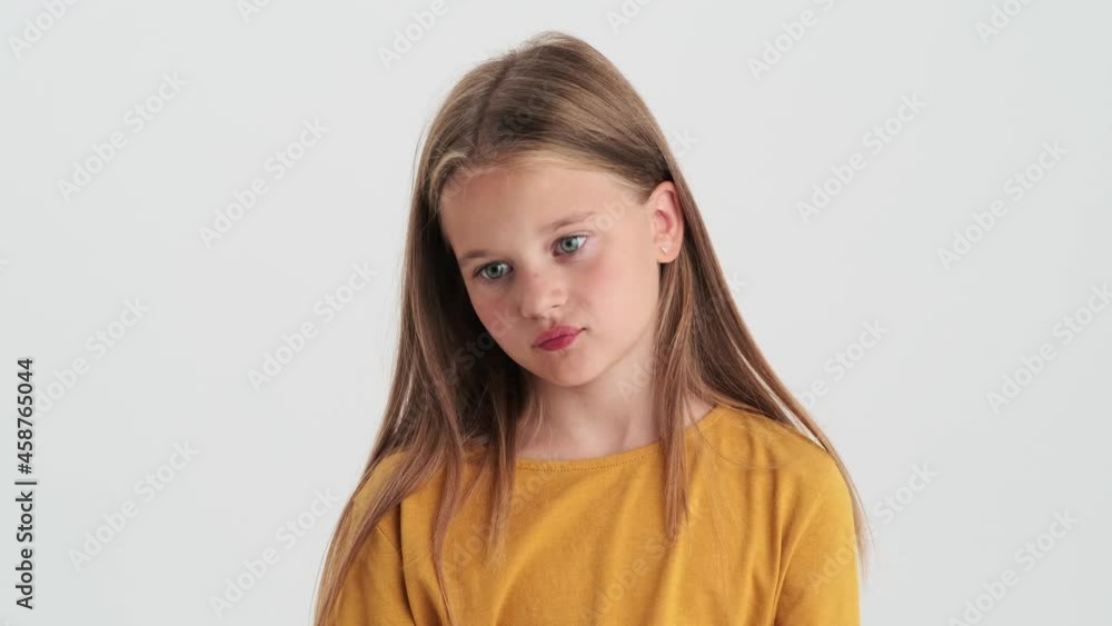 A disappointed small girl standing isolated over a gray wall in the studio A disappointed small girl standing isolated over a gray wall in the studio