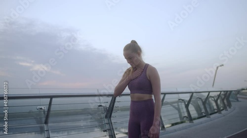 Athletic woman heavily breathing during jog along bridge, exhaustive training