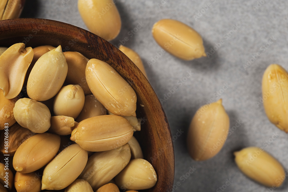 Peanuts in wooden bamboo bowl on concrete background. Nuts. Peanuts in wooden bamboo bowl on concrete background. Nuts.