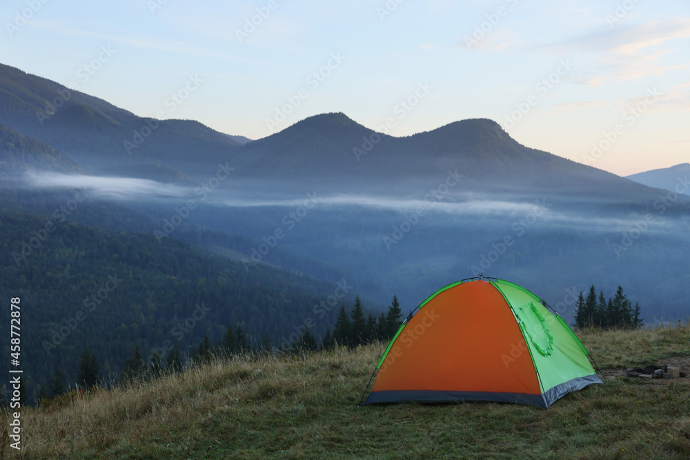 Picturesque mountain landscape with camping tent in morning