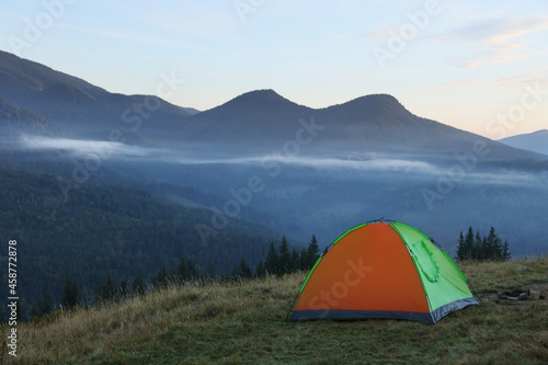 Picturesque mountain landscape with camping tent in morning