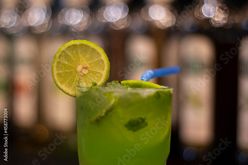 Green cocktail with lime and ice and blue straw