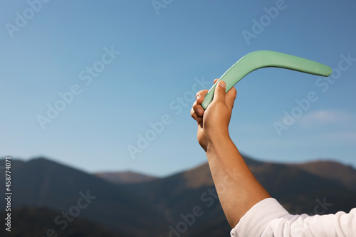 Man throwing boomerang in mountains, closeup. Space for text