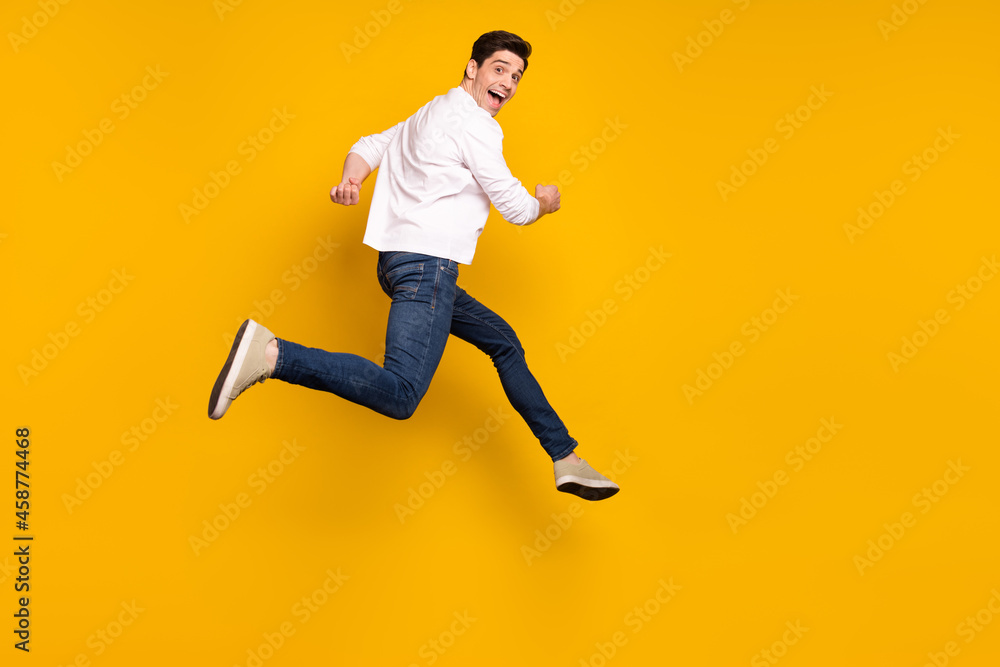 Full length profile photo of cool brunet young guy run wear shirt jeans sneakers isolated on yellow background