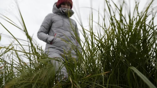 A Woman Walks on the Shore of a Lake In Windy and Cold Autumn Weather