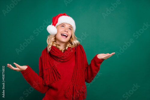 Photo of young girl happy positive smile hold hands look empty space x-mas atmosphere isolated over green color background