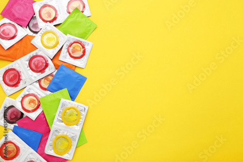 Colorful condoms on yellow background
