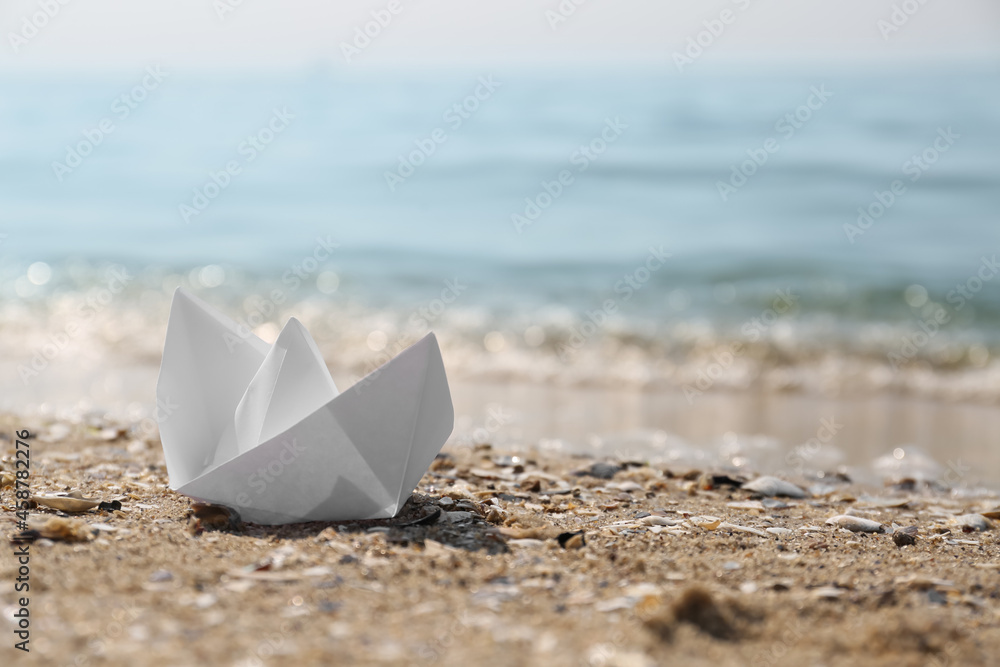 White paper boat on sandy beach near sea, space for text White paper boat on sandy beach near sea, space for text