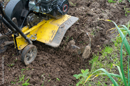 Man plows the land with a cultivator. Agricultural machinery: cultivator for tillage in the garden.