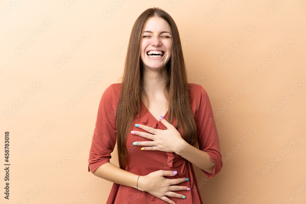 Obraz premium Young caucasian woman isolated on beige background smiling a lot