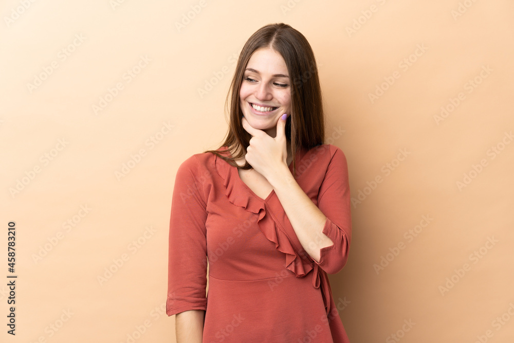 Young caucasian woman isolated on beige background looking to the side and smiling Young caucasian woman isolated on beige background looking to the side and smiling