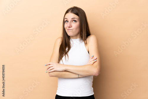 Young caucasian woman isolated on beige background making doubts gesture while lifting the shoulders