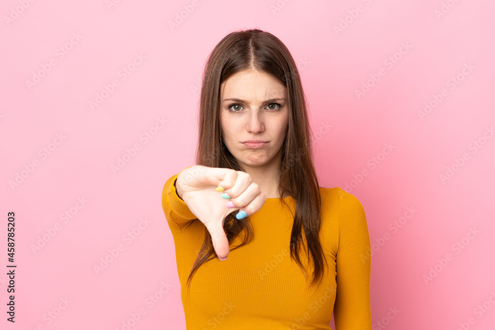 Young caucasian woman isolated on pink background showing thumb down with negative expression Young caucasian woman isolated on pink background showing thumb down with negative expression