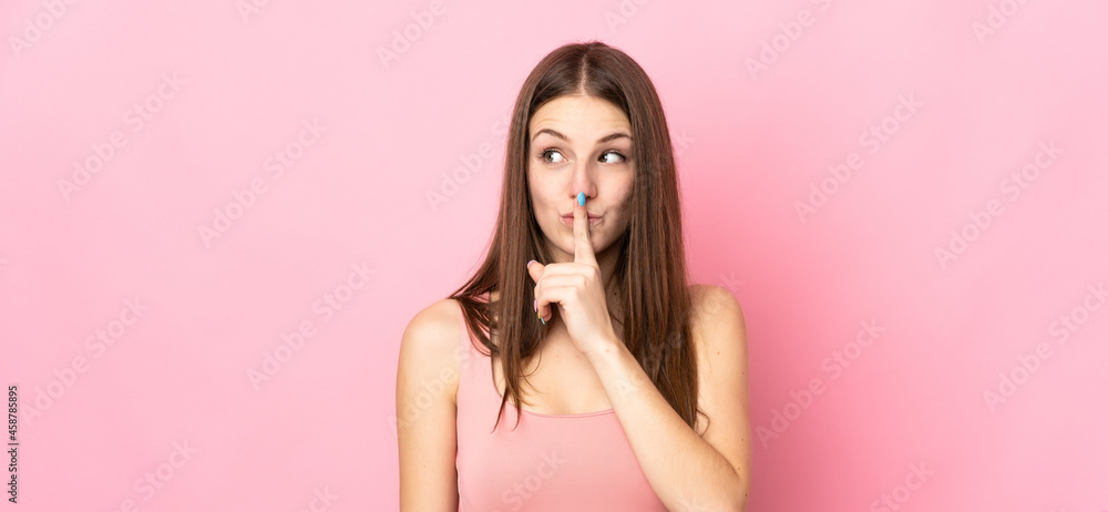 Young caucasian woman isolated on pink background showing a sign of silence gesture putting finger in mouth