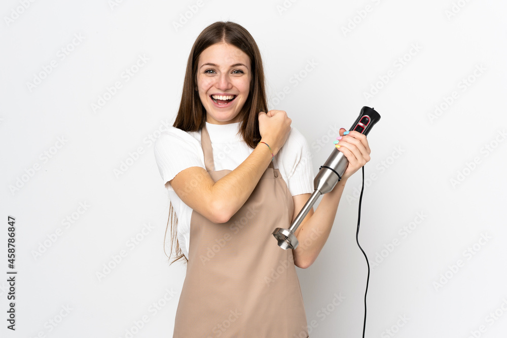 Young woman using hand blender isolated on white background celebrating a victory Young woman using hand blender isolated on white background celebrating a victory