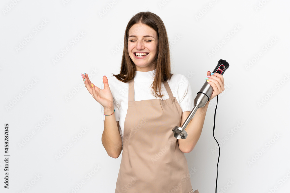 Young woman using hand blender isolated on white background laughing Young woman using hand blender isolated on white background laughing
