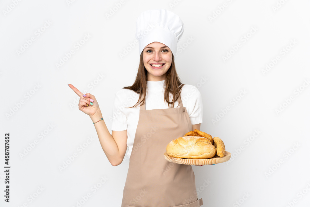 Young woman in chef uniform isolated on white background pointing finger to the side Young woman in chef uniform isolated on white background pointing finger to the side