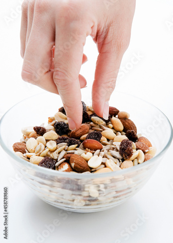 Woman, Girl Picking at a Bowl of Nuts. Dried Fruits in a Glass Bowl