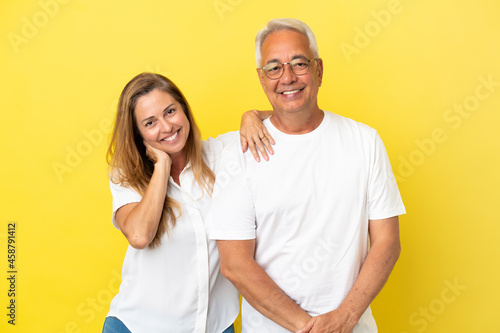 Middle age couple isolated on yellow background happy and laughing
