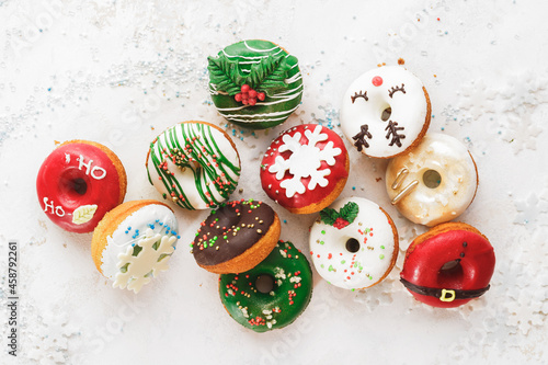 Homemade Glazed Christmas Donuts. Assorted homemade glazed donuts with sprinkles on white festive background. Top view, blank space

