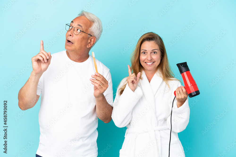 Middle age couple holding dryer and toothbrush isolated on blue background thinking an idea pointing the finger up Middle age couple holding dryer and toothbrush isolated on blue background thinking an idea pointing the finger up