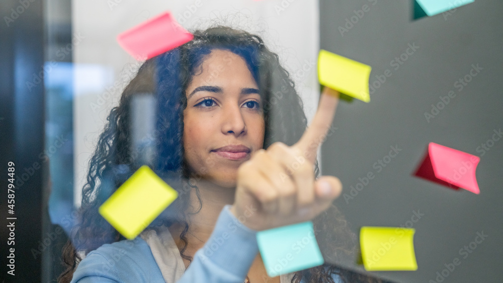 Business people meeting at office. Woman use post it notes to share idea. Brainstorming concept. Sticky note on glass wall, decision time. Business people meeting at office. Woman use post it notes to share idea. Brainstorming concept. Sticky note on glass wall, decision time.