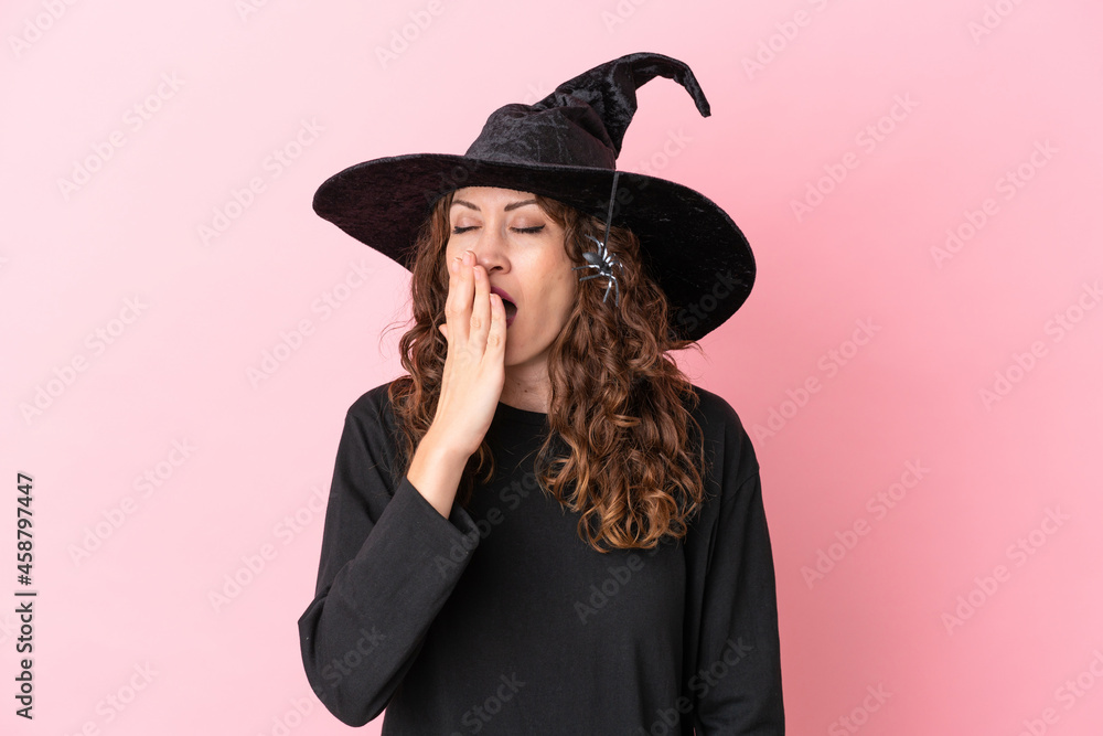 Young caucasian woman celebrating halloween isolated on pink background yawning and covering wide open mouth with hand