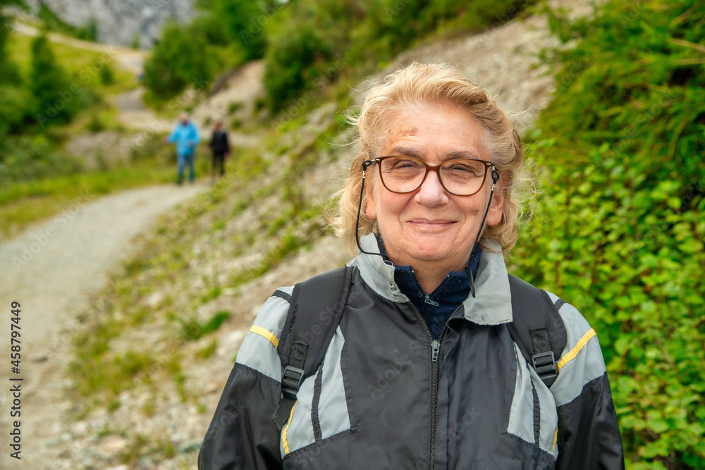 Happy elderly woman relaxing in the middle of a mountain trip.