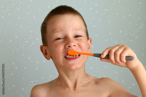 A boy brushes his teeth on a blue background