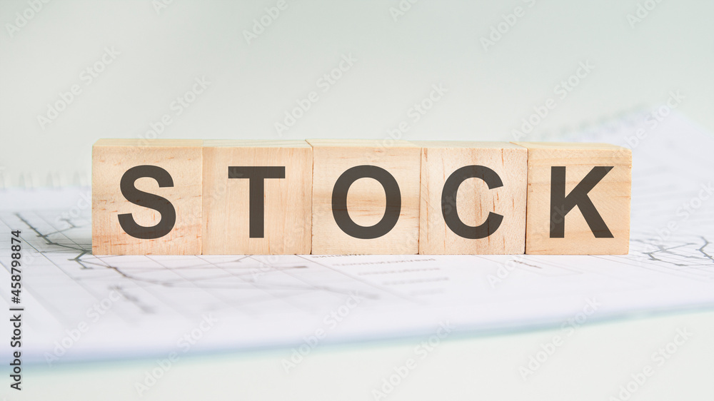 stock is written on light wooden blocks. the word is located on a sheet with charts and graphs stock is written on light wooden blocks. the word is located on a sheet with charts and graphs