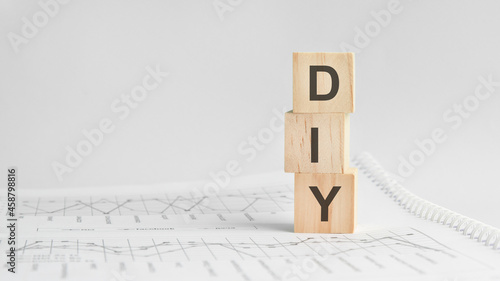 three stone cubes on the background of white financial statements, tables with the word DIY. Strong business concept