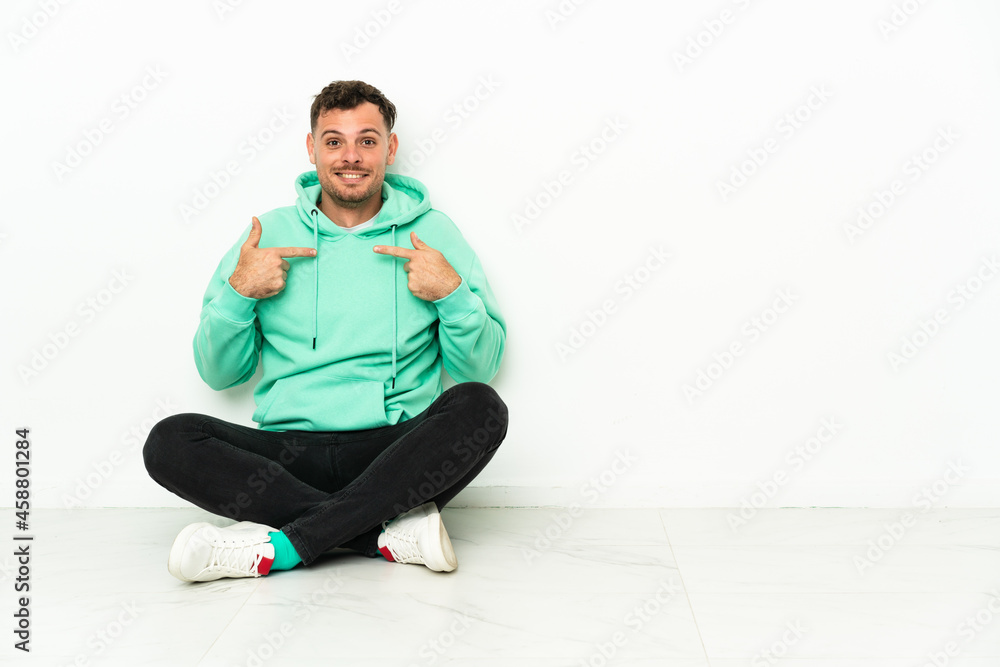 Young handsome caucasian man sitting on the floor with surprise facial expression