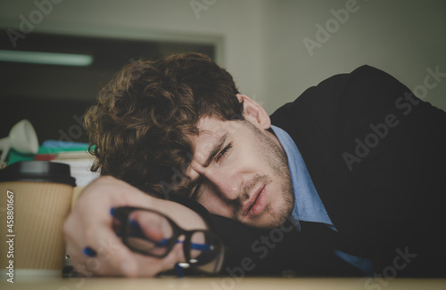 Hopeless business man resting on the office desk with frustation emotion and exhausted face. photo