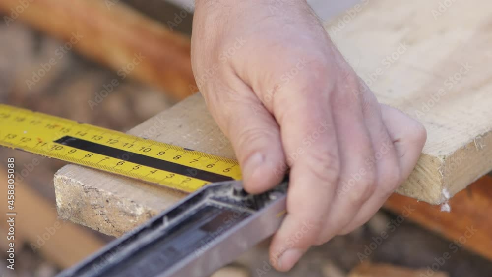 a man marks the necessary dimensions on the blackboard with a pencil and a square, carpentry work a man marks the necessary dimensions on the blackboard with a pencil and a square, carpentry work