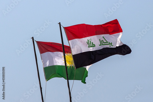 Flags of Iraq and the Autonomous Region of Iraqi Kurdistan on a background of blue sky.