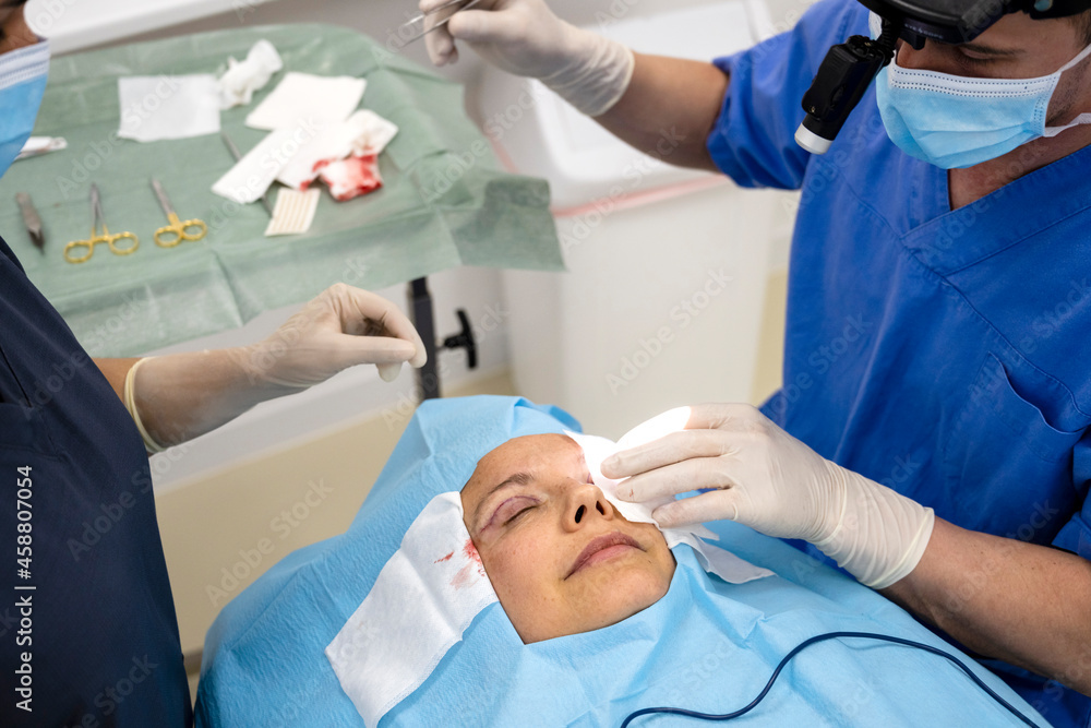 Surgeons performing eyelid surgery to anonymous patient Surgeons performing eyelid surgery to anonymous patient