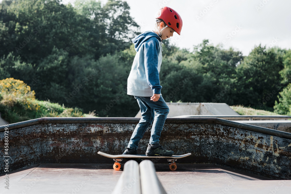 boy skateboarding with a helmet on at a skate park in the UK Stock