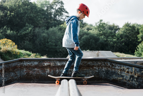 boy skateboarding with a helmet on at a skate park in the UK photo
