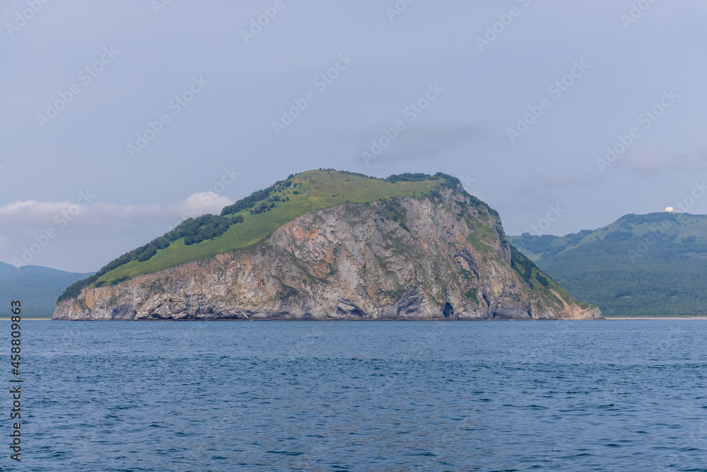 An island in the ocean is hidden by fog and low clouds in the vicinity of Kamchatka.