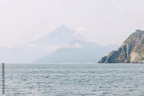 Photo of a volcano in Kamchatka in low clouds and fog with haze from the Pacific Ocean
