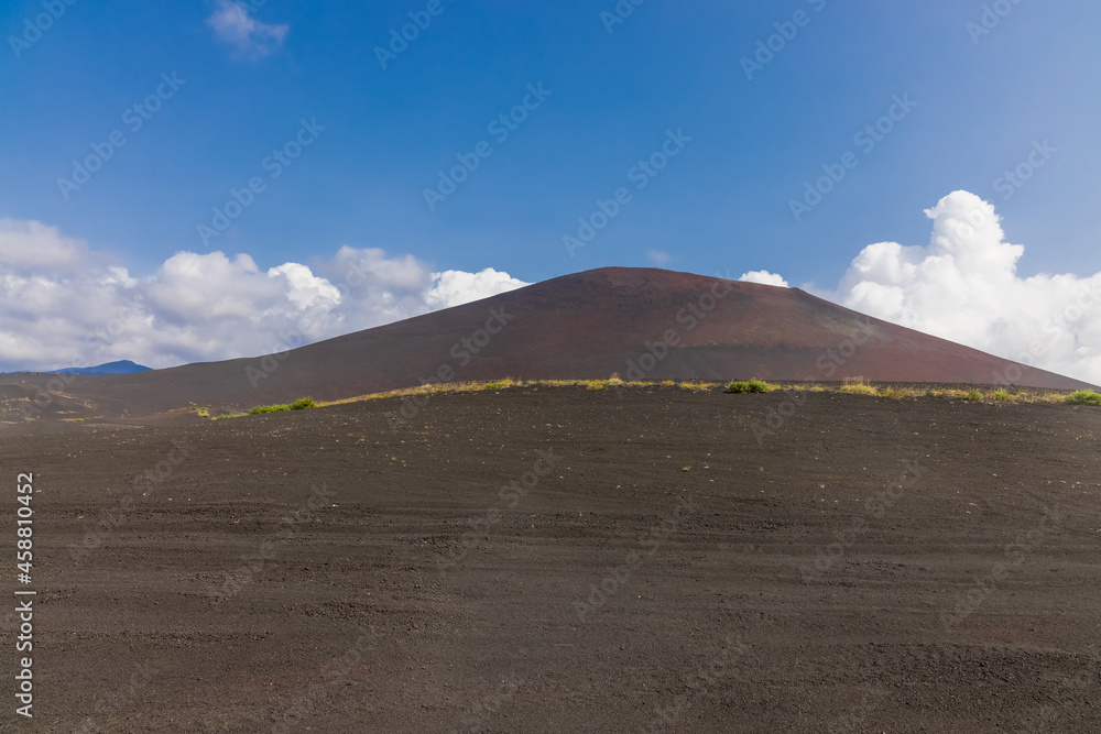 Volcanic-lunar landscape in Kamchatka, rocks from volcanic rocks against the background of a blue sky with clouds. Klyuchevskaya group of volcanoes. Volcanic-lunar landscape in Kamchatka, rocks from volcanic rocks against the background of a blue sky with clouds. Klyuchevskaya group of volcanoes.