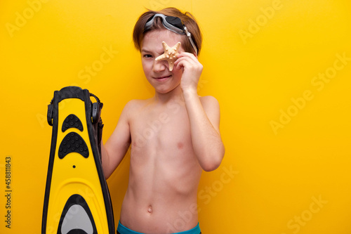 Close-up boy with flippers and starfish with yellow background. Traveling on vacation at sea with children. Summer vacation at school basis for banner photo