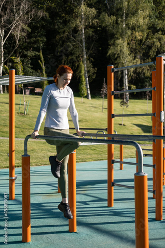 athletic ginger woman working out outdoor on urban sports ground in sunny autumn day