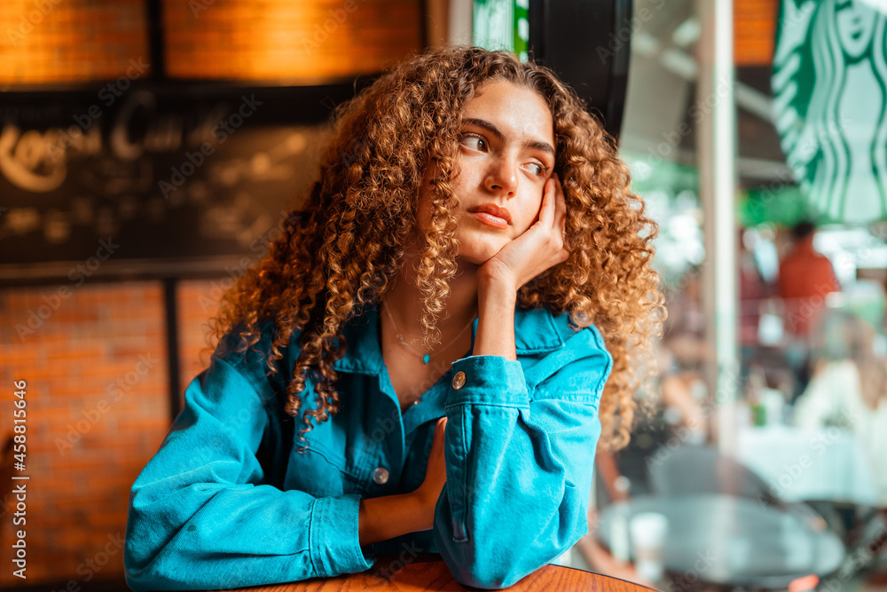 curly haired girl sitting and looking through the window curly haired girl sitting and looking through the window