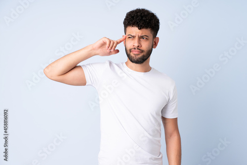 Young Moroccan man isolated on blue background making the gesture of madness putting finger on the head
