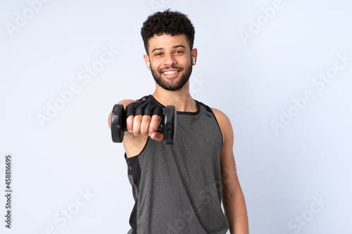 Young Moroccan man isolated on blue background making weightlifting © luismolinero