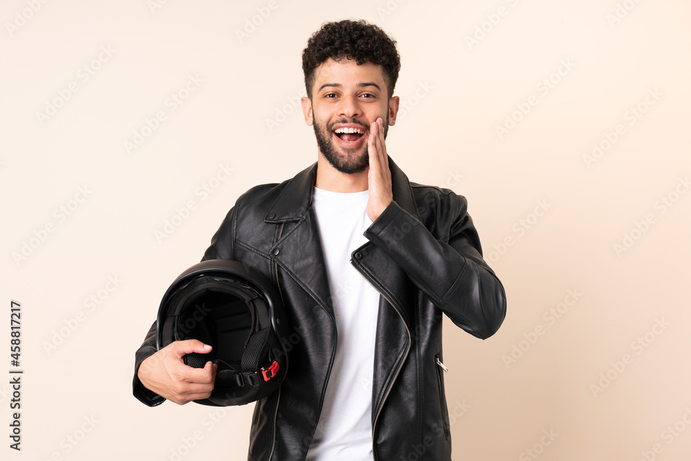 Young Moroccan man with a motorcycle helmet isolated on beige background with surprise and shocked facial expression Young Moroccan man with a motorcycle helmet isolated on beige background with surprise and shocked facial expression