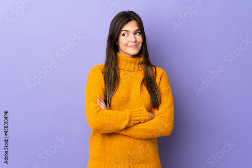 Teenager Brazilian girl over isolated purple background having doubts while looking side © luismolinero