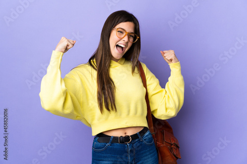 Teenager Brazilian student girl over isolated purple background celebrating a victory