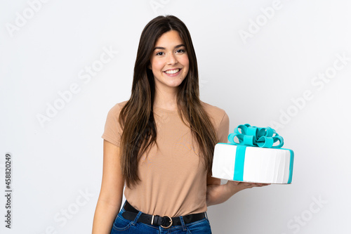 Teenager pastry chef holding a big cake over isolated white background smiling a lot © luismolinero